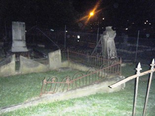 Apparition leaning on large headstone